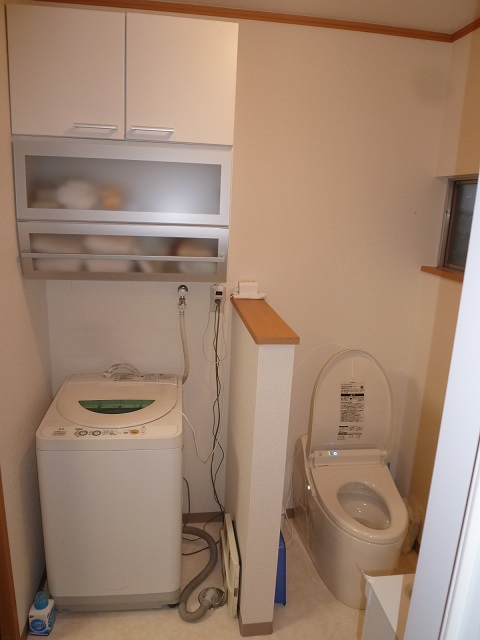 洗面台向かいの洗濯機とトイレ。間の腰壁の高さは、入口からトイレが隠れて、窓からの光をなるべく遮らないよう配慮しました。